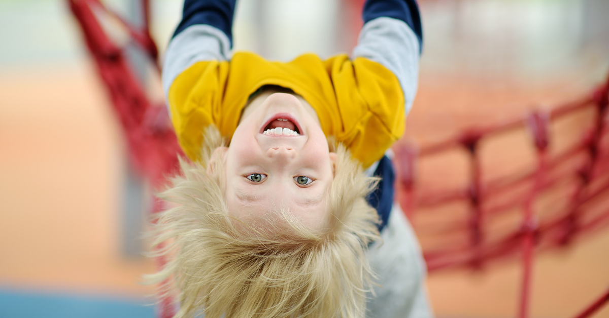 Kind hängt kopfüber auf einem Spielplatz – starker Bewegungsdrang ist nicht automatisch ein Zeichen für ADHS bei Kindern