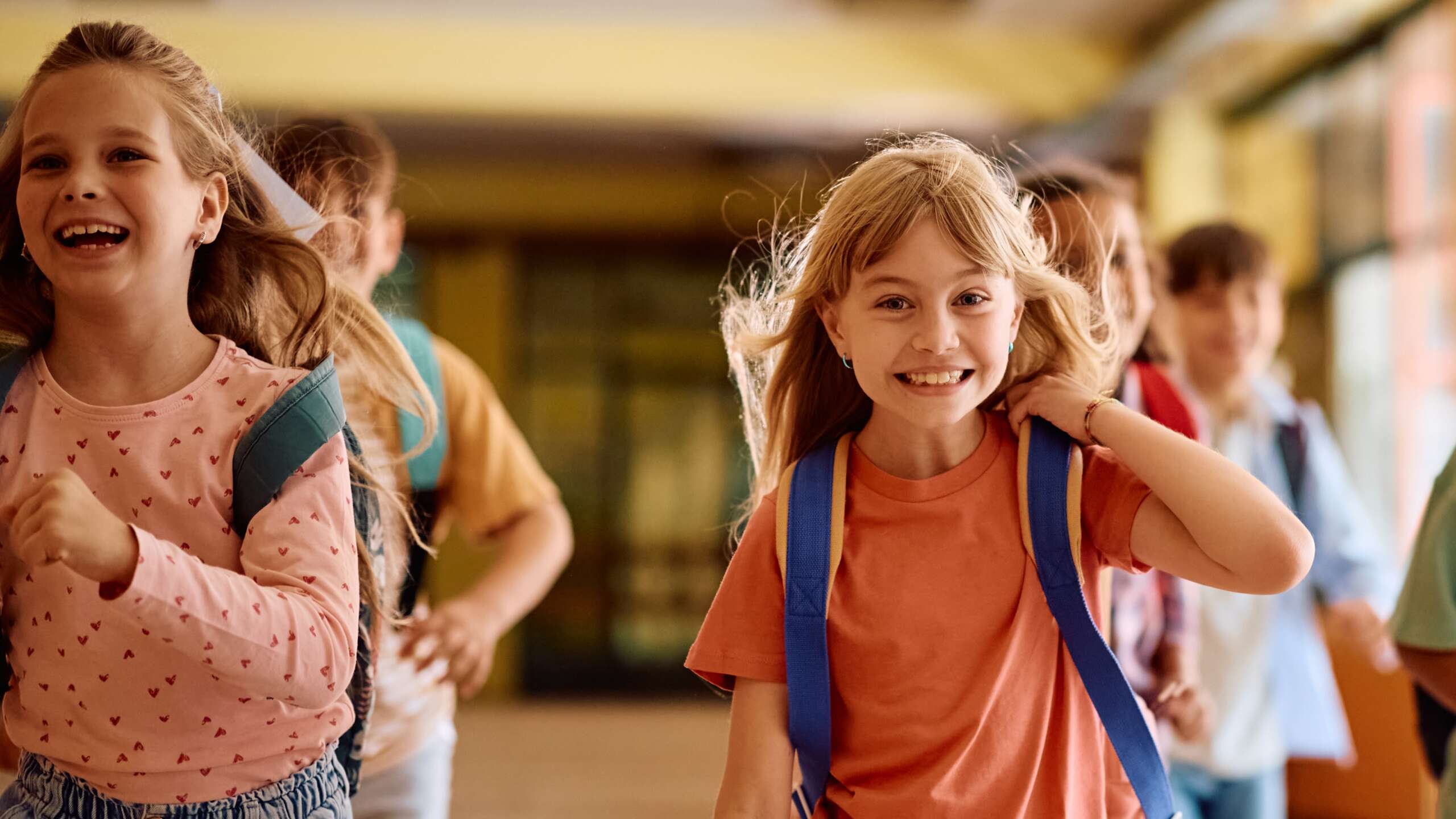 Glückliche Schulkinder zum Schulstart laufen gemeinsam im Flur.